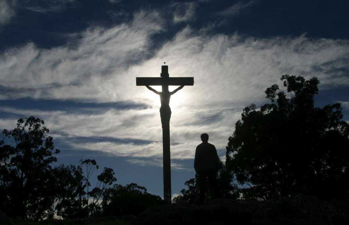 A man stands in front of a cross with an statue of Jesus Chirst during a Holy Week procession in Tandil, Argentina, Thursday, April 1, 2010. (AP Photo/Pablo Aneli)