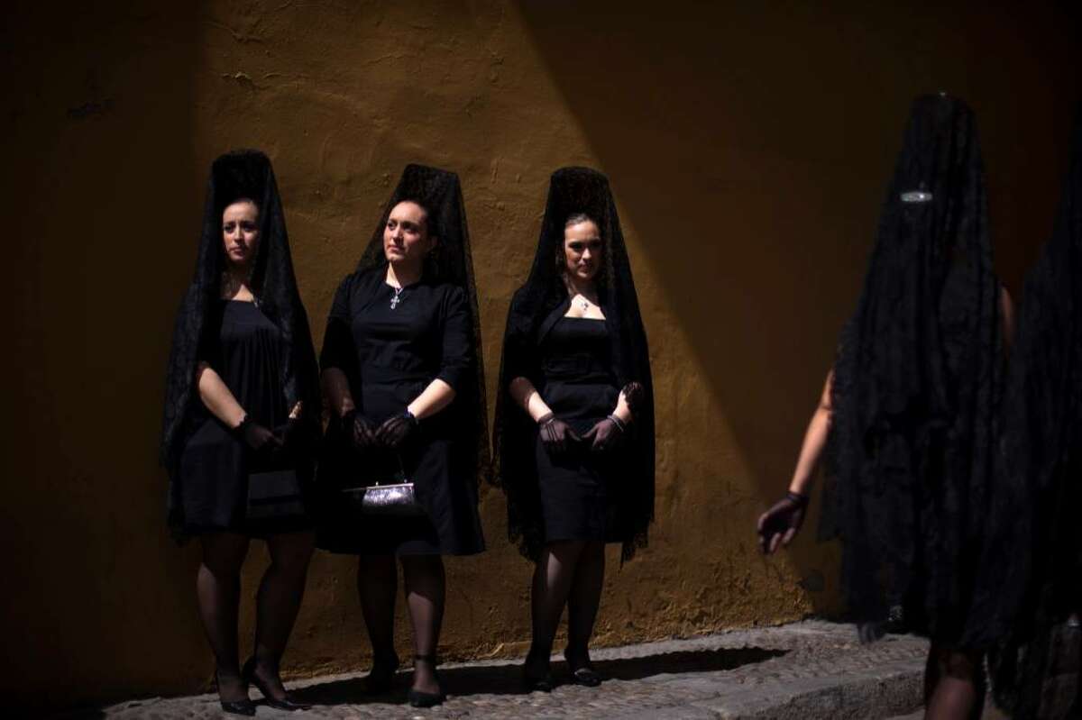 Women wearing the traditional mantilla pose for a photo at the entrance gate of La Macarena church before taking part in a procession during Holy Week in Seville, Spain, Southern Spain, Thursday, April 1, 2010. (AP Photo/Emilio Morenatti)
