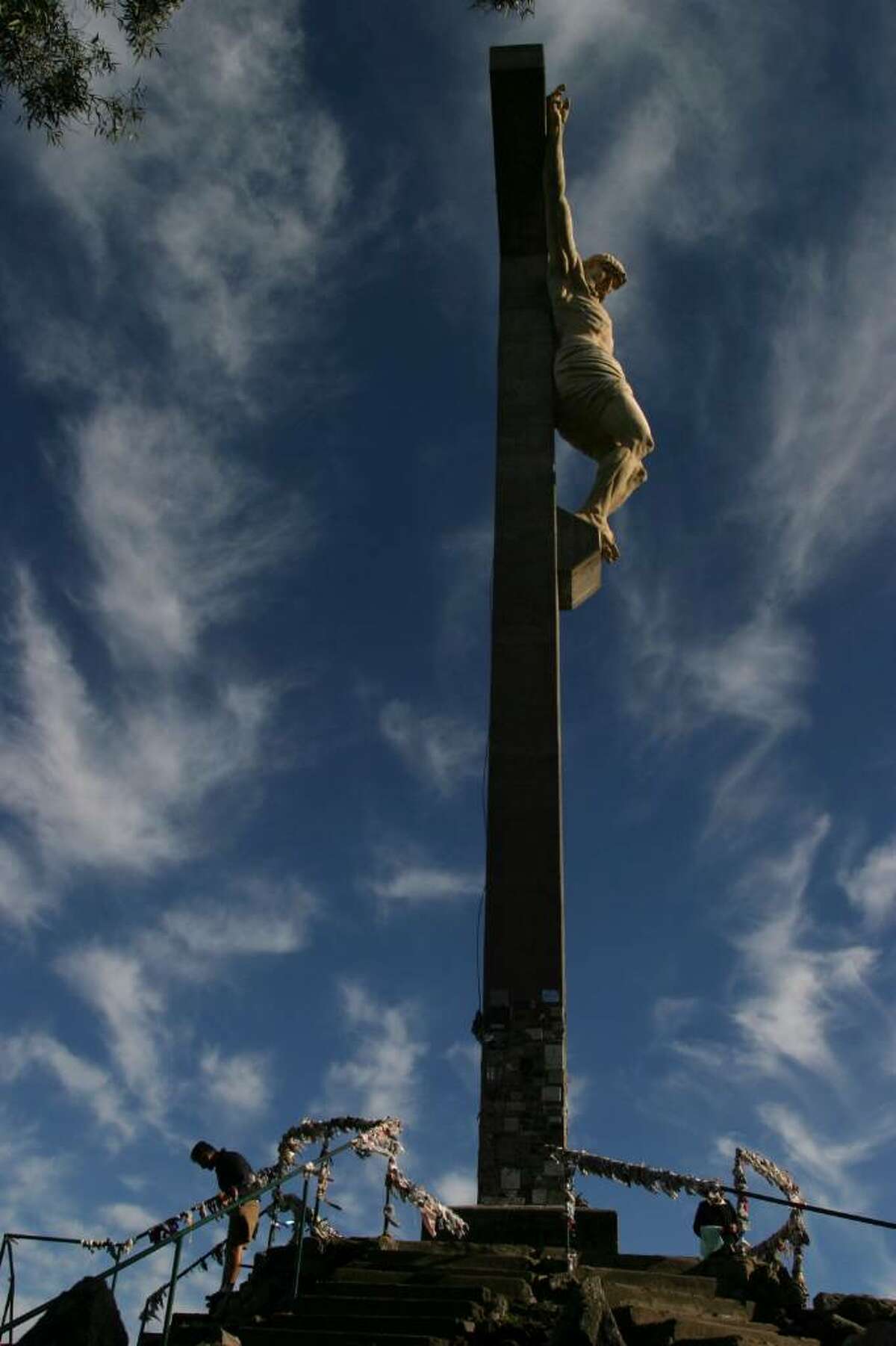 People walk past a cross with an statue of Jesus Christ during a Holy Week procession in Tandil, Argentina, Thursday, April 1, 2010. (AP Photo/Pablo Aneli)