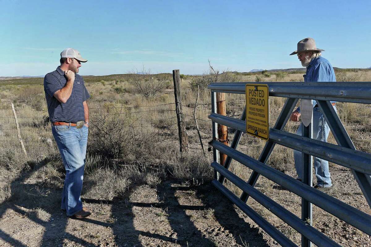 Robert Jackson, left, waits as James Spriggs, 69, opens the gate of the family's 4,400-acre ranch south of Marfa, Texas in the Big Bend County Tuesday, Dec. 8, 2015. The Trans-Pecos Pipeline Project will run through the ranch and Spriggs spent months trying to fight the company but on advise from his lawyer, the family relented and let pipeline surveyors on his property this week. Jackson was with the surveying group. "The oil companies and pipeline companies own Texas, and they do whatever they damn well please," he said.