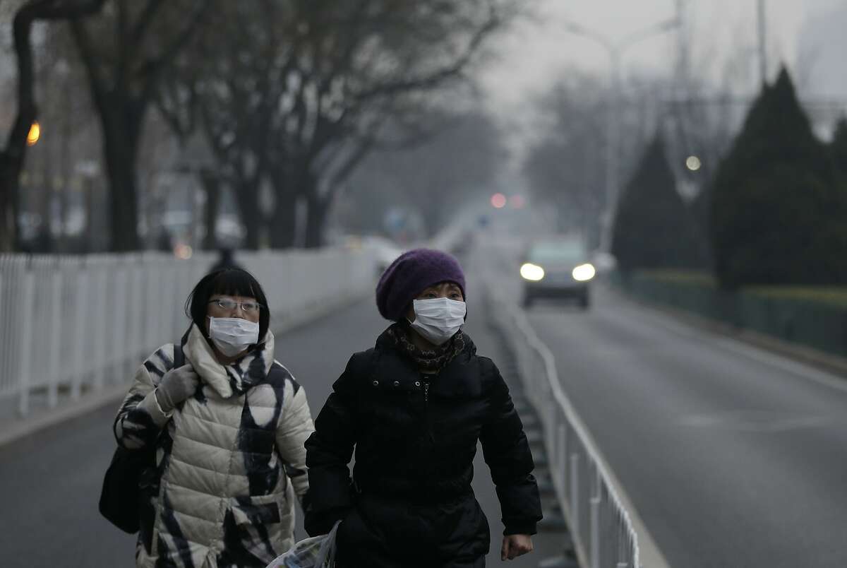 Women wear masks as they walk along a street on a polluted day in Beijing, Sunday, Dec. 13, 2015. China's push for a global climate pact is partly because of its own increasingly pressing need to solve serious environmental problems, observers said Sunday. (AP Photo/Andy Wong)