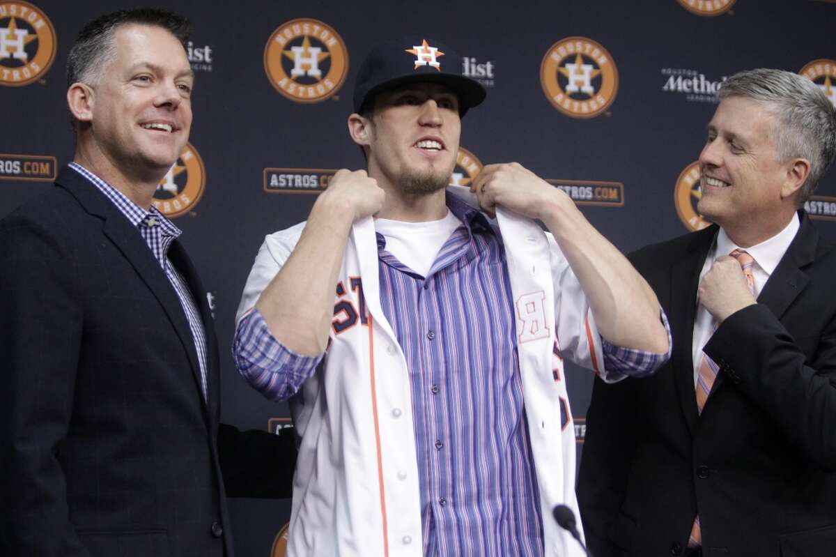 Houston Astros manager A.J. Hinch, left, waits as newly-acquired pitcher Ken Giles, center, puts on his new jersey with help from general manager Jeff Luhnow, right, during a news conference at Minute Maid Park Monday, Dec. 14, 2015, in Houston. ( Melissa Phillip / Houston Chronicle )
