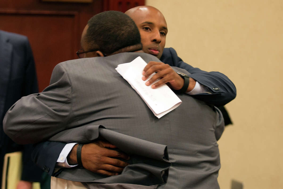 Jay High School principal Robert Harris (left) hugs former assistant football coach Mack Breed as they appear at a UIL hearing on Oct. 15, 2015, in Round Rock.