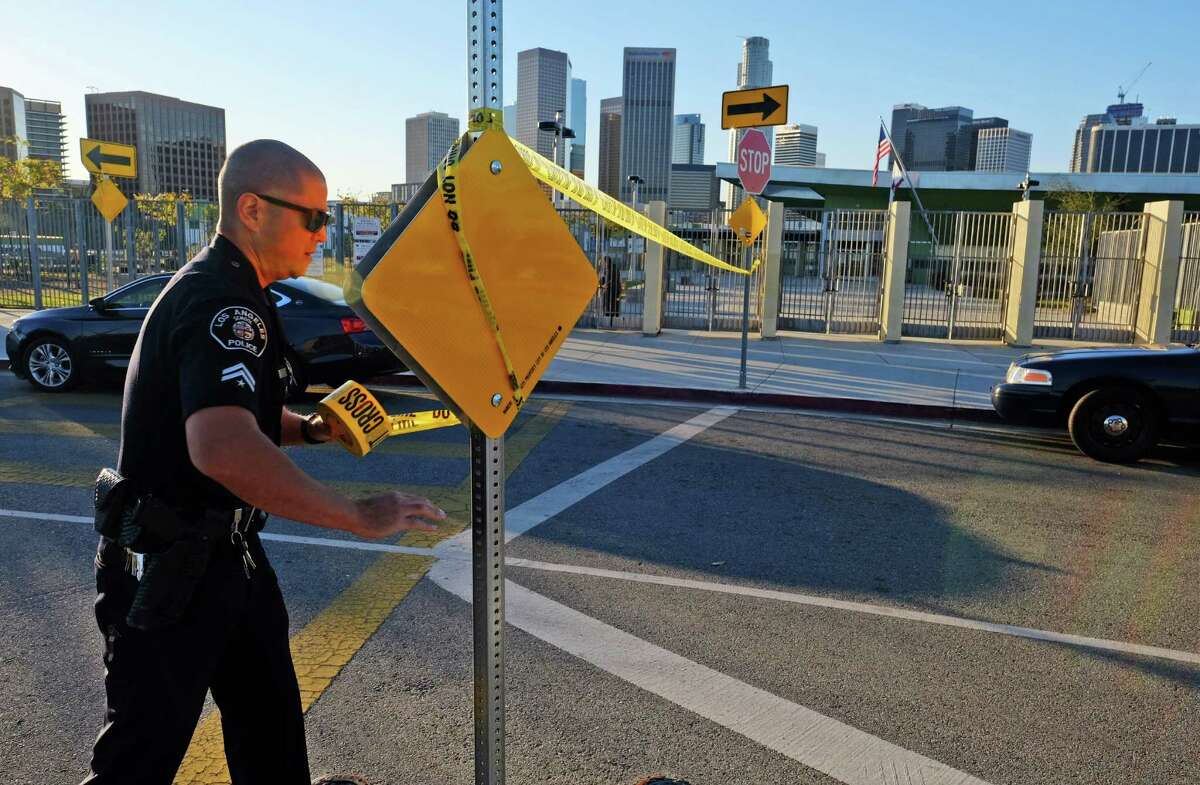 A police officer puts up yellow tape to close Edward Roybal Hich School in Los Angeles on Tuesday. L.A. schools closed after a terror threat was emailed to a school board member.