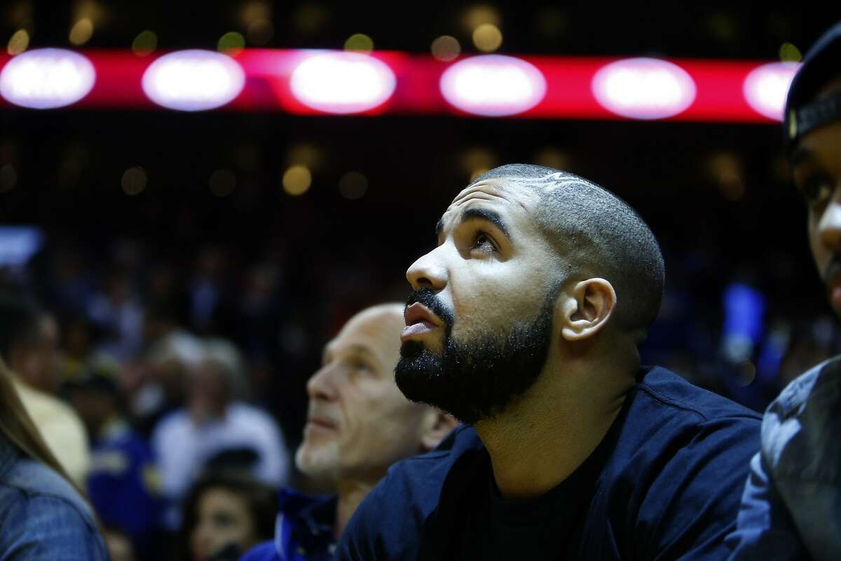 Drake watches the Golden State Warriors play Phoenix Suns in NBA game at Oracle Arena in Oakland, Calif., on Wednesday, December 16, 2015.