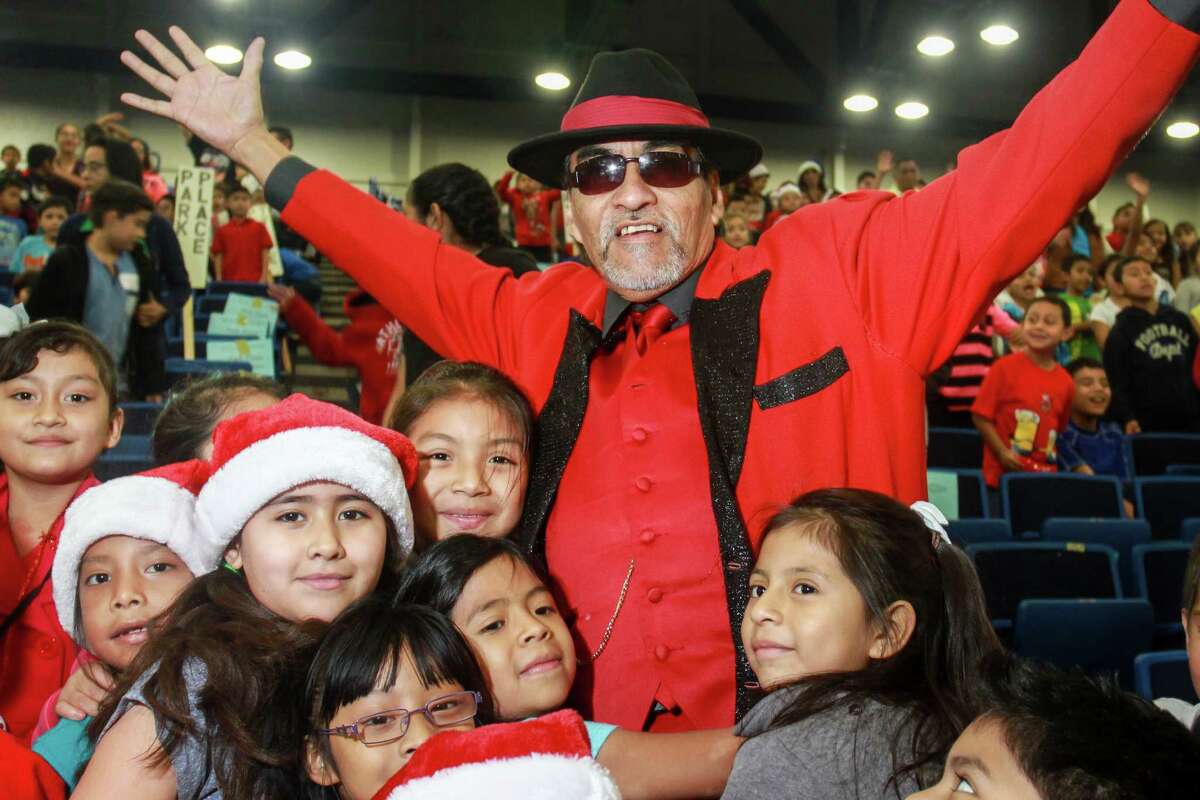 Richard Reyes, or Pancho Claus, is surrounded by students at the Navidad En El Barrio annual Christmas Program at George R. Brown Convention Center. Over 2,000 children from 50 different elementary schools attend the toy giveaway.