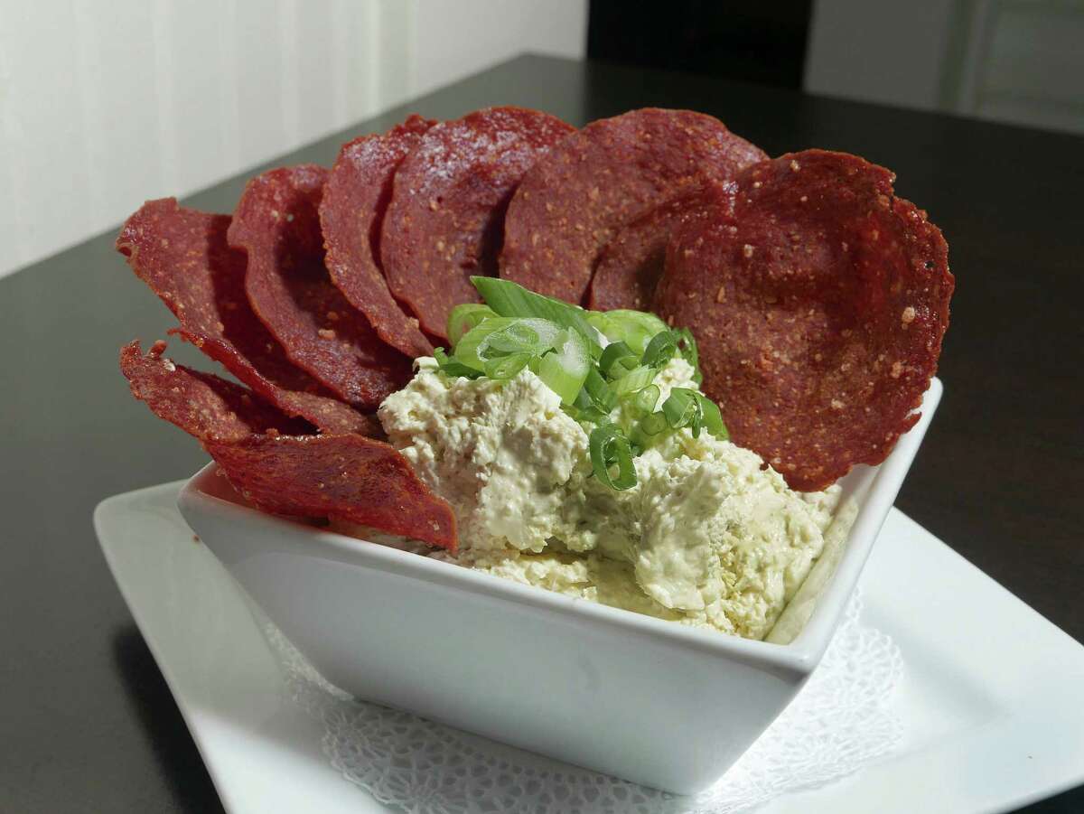 Thin slices of salami are baked until crisp and serve as chips with a dip of sweet and hot pickled jalapeños with cream cheese.