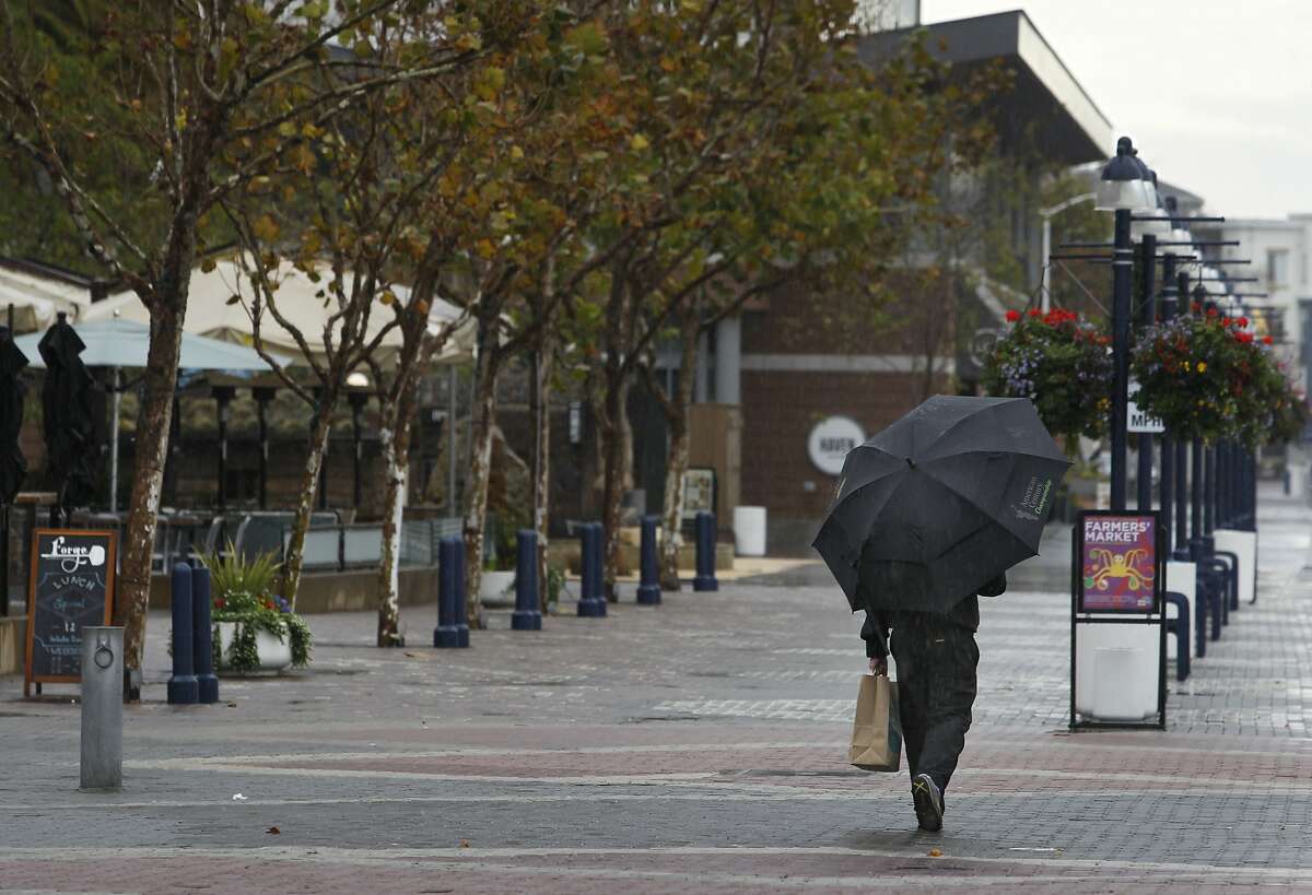 Keith DuBay walks back home through the rain at Jack London Square in Oakland, Calif. on Thursday, Dec. 24, 2015.