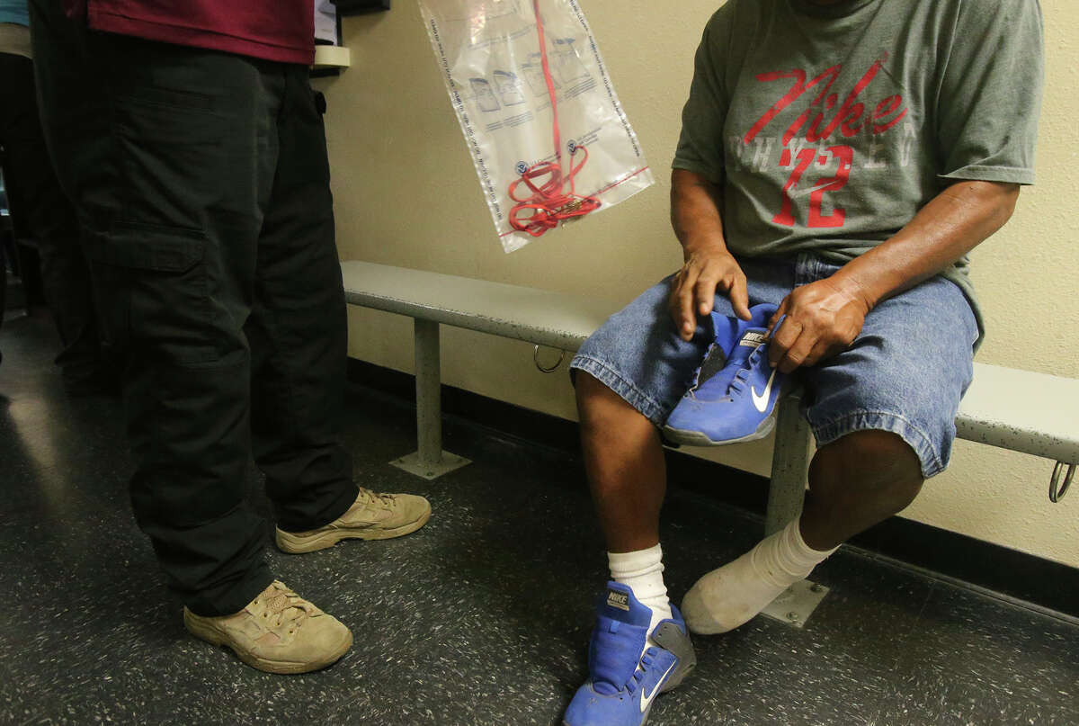 An Immigration and Customs Enforcement (ICE) officer places personal belongings in a bag after arresting a man (right) Monday August 17, 2015. The agency was conducting a target enforcement operation to round up immigrants with warrants and outstanding deportation orders.