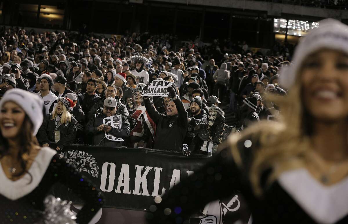 A Raiders fan holds a sign saying "Stay in Oakland," as the Oakland Raiders played the San Diego Chargers at O.Co Coliseum in Oakland, Calif., on Thursday, December 24, 2015.