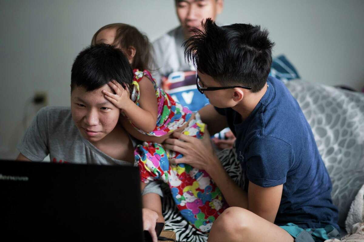 Trung Ngo, left, 17, a﻿n immigrant from Vietnam, tries to ﻿focus on an English vocabulary lesson as his little cousin Anh Nguyen, 1, tries to get his attention at the apartment he shares with his uncle, aunt, mother, brother and cousins.﻿