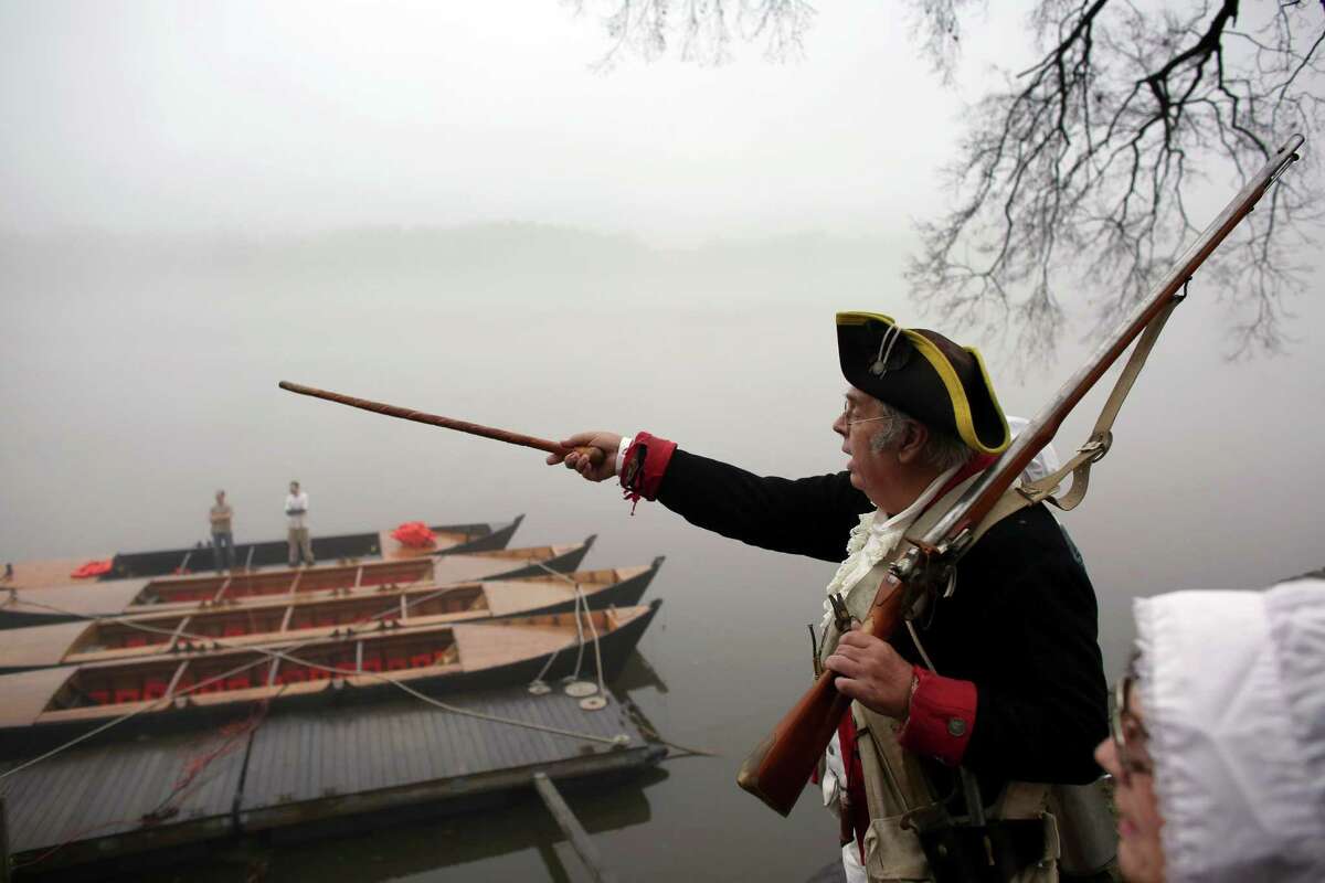 Re-enactor Bill Strunk points across the Delaware River on Friday before the portrayal of Washington’s historic crossing that changed the Revolutionary War.