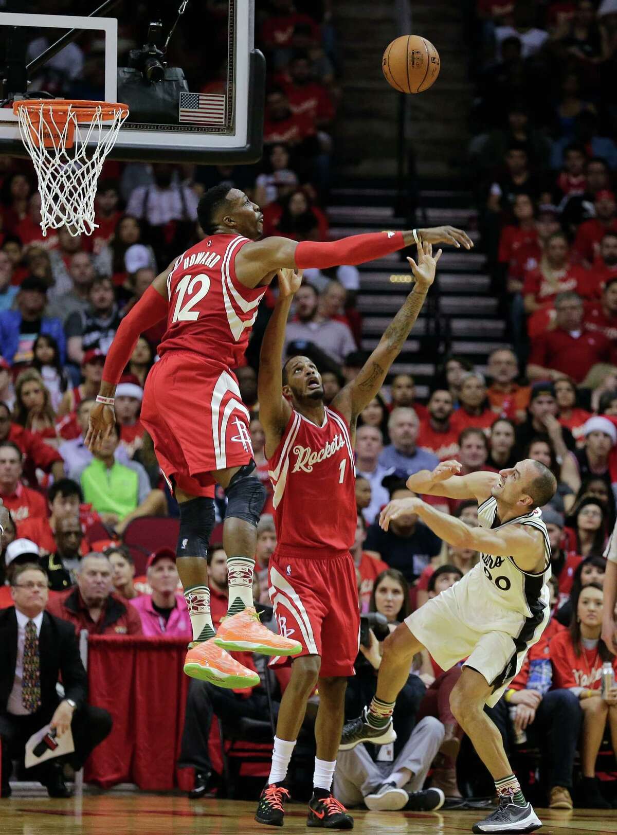 San Antonio Spurs guard Manu Ginobili (20) is fouled by Houston Rockets forward Trevor Ariza (1) as center Dwight Howard (12) blocks his shot attempt in the first half of an NBA basketball game Friday, Dec. 25, 2015, in Houston. (AP Photo/Bob Levey)