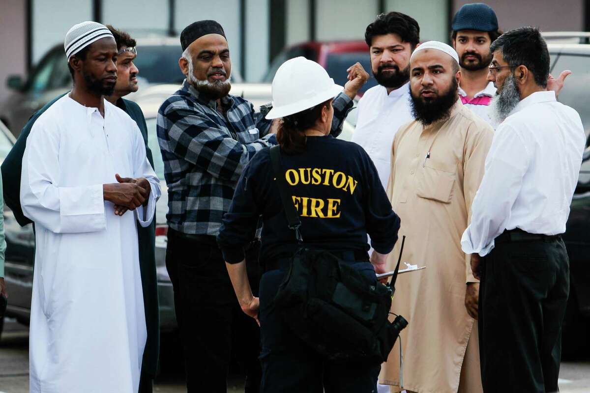 A Houston fire fighter talks to a group of men near the site of a fire at a mosque off Wilcrest Drive Friday, Dec. 25, 2015, in Houston. No one was injured in the blaze, which started around 2:30 p.m., and authorities are still investigating whether or not there was foul play involved. ( Michael Ciaglo / Houston Chronicle )
