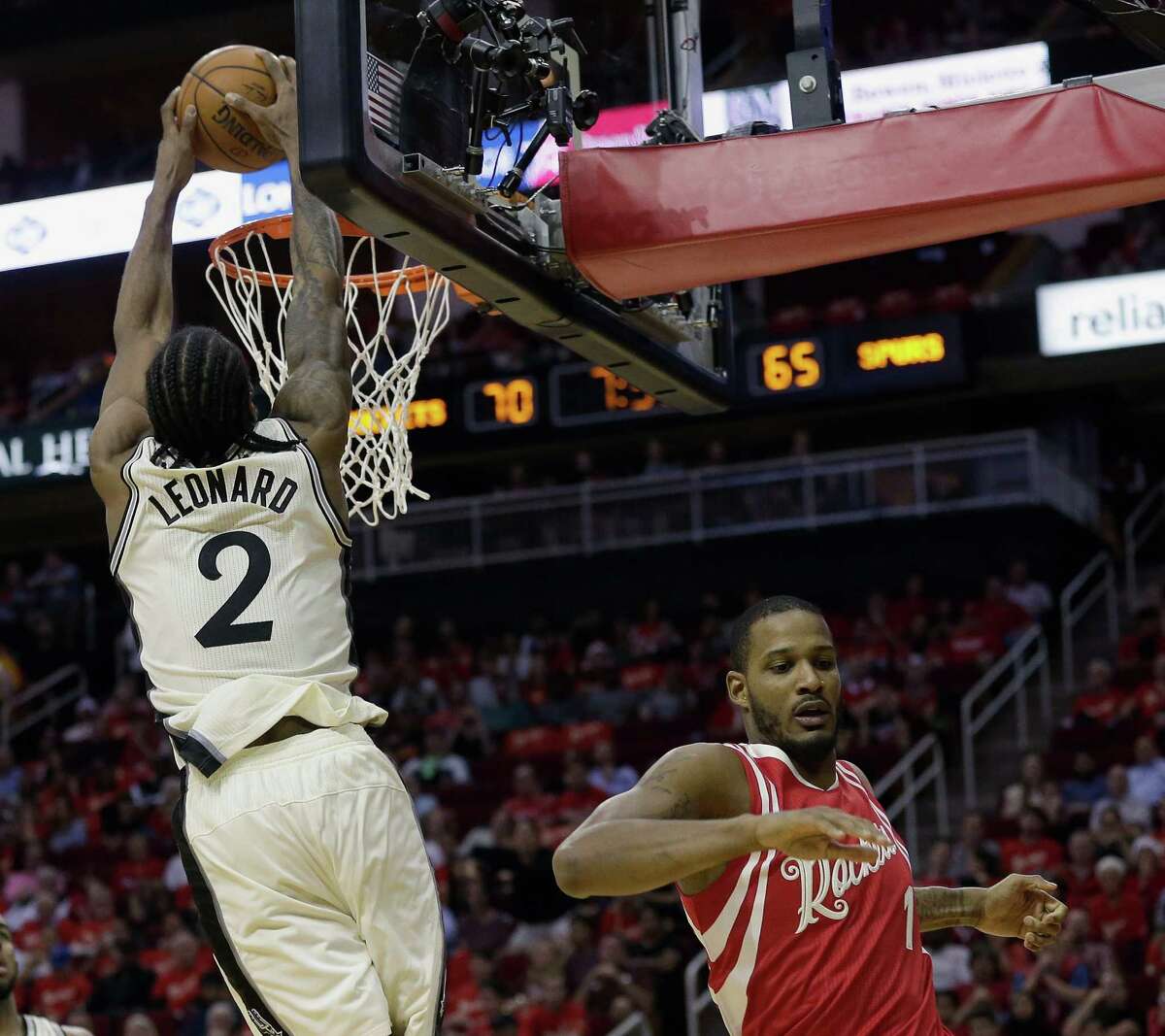 San Antonio Spurs forward Kawhi Leonard (2) dunks as Houston Rockets forward Trevor Ariza (1) runs under the basket in the second half of an NBA basketball game Friday, Dec. 25, 2015, in Houston. Houston won 88-84. (AP Photo/Bob Levey)