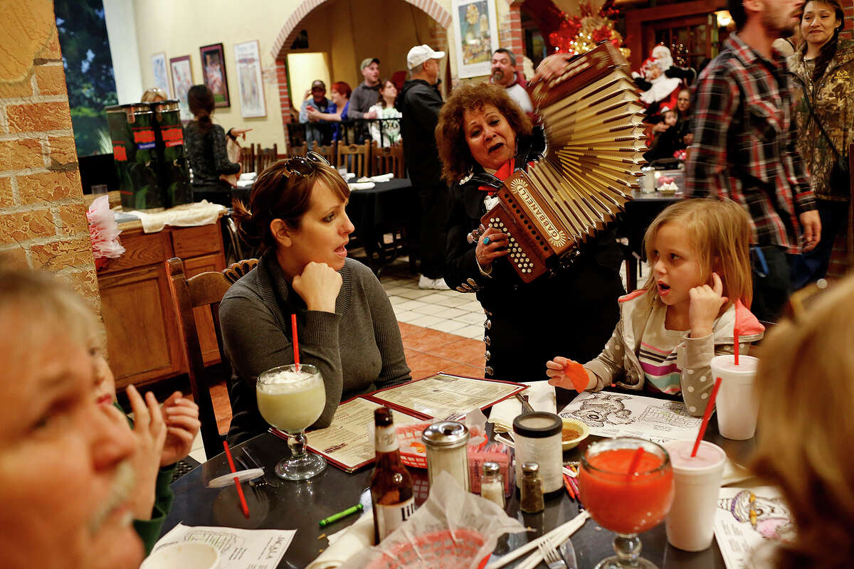 Eva Ybarra sings and plays her accordion for families including Brooke Matherne and her daughter, Sophia Matherne, 6, at Jacala Mexican Restaurant in San Antonio on Friday, December 18, 2015.