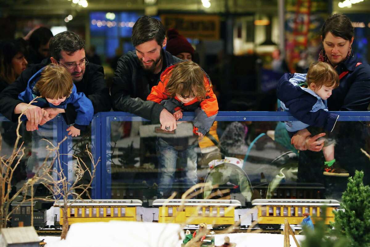 (from left) Brendan, Jason and Shannon Huza hold Charles, Marek and Marlowe as they watch the trains go round the Winter Village at the Seattle Center's WinterFest, Dec. 28, 2015.