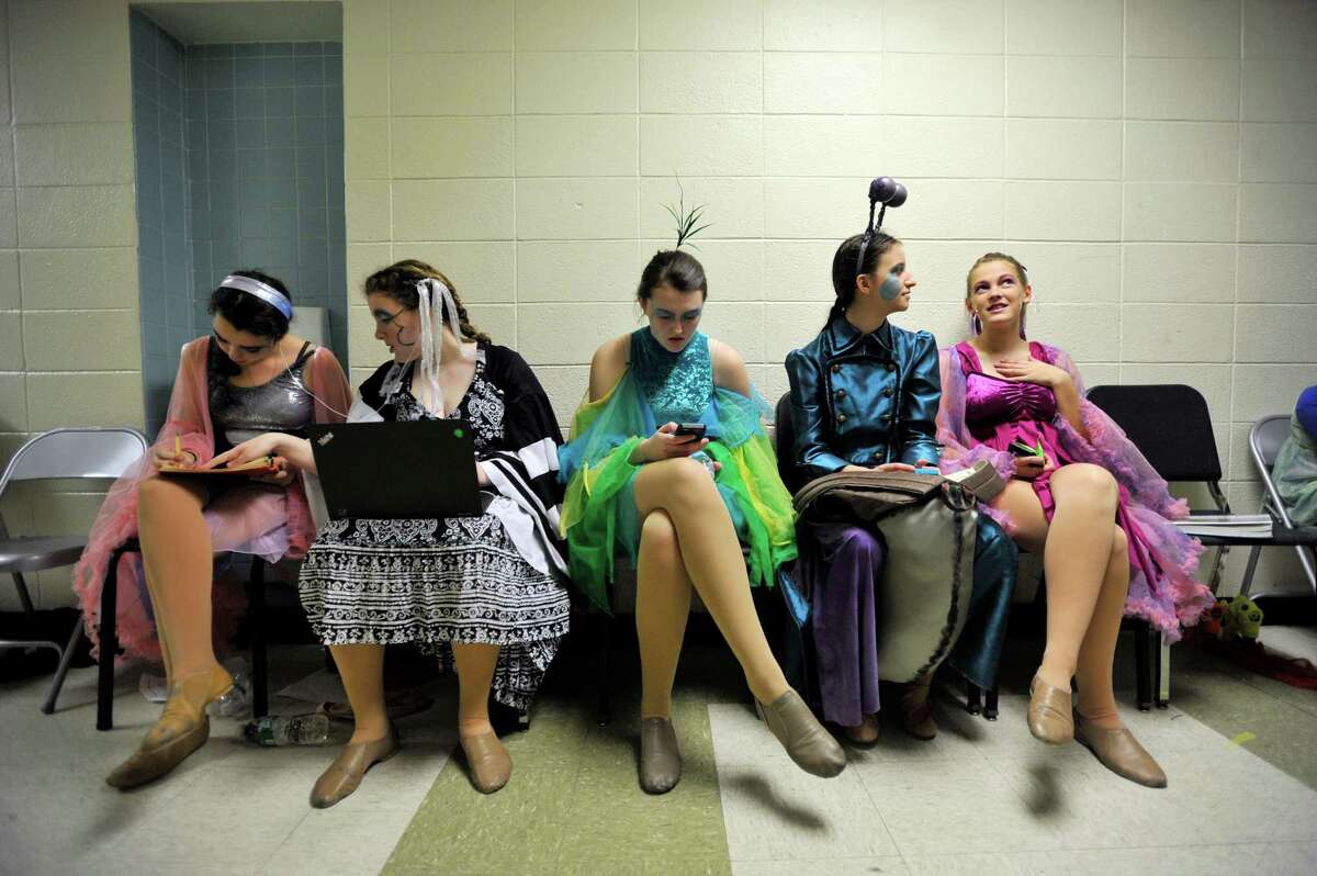 The cast of The Little Mermaid occupy themselves before showtime, with some opting to do homework and others opting to talk or text.