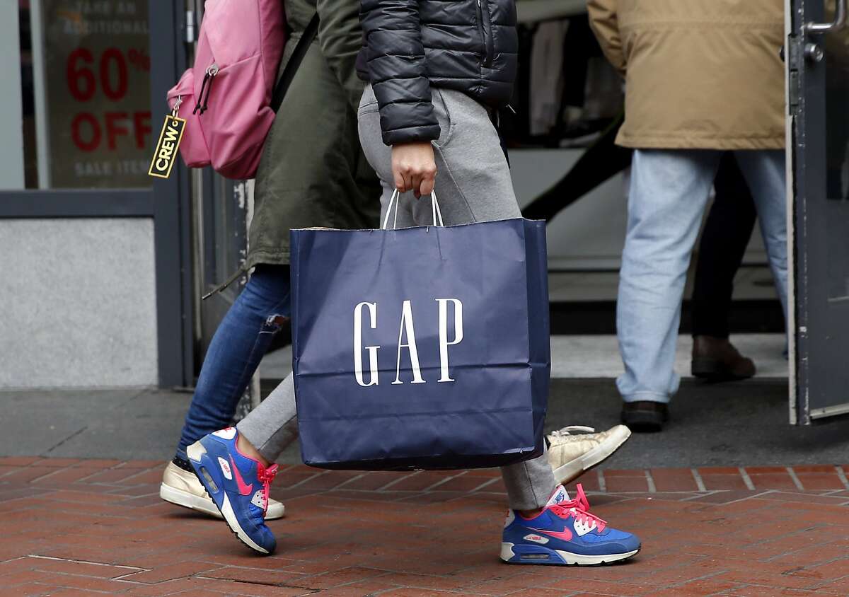 A shopper carries a Gap bag in front of the store on Market Street in San Francisco, California, on Wednesday, Dec. 30, 2015.