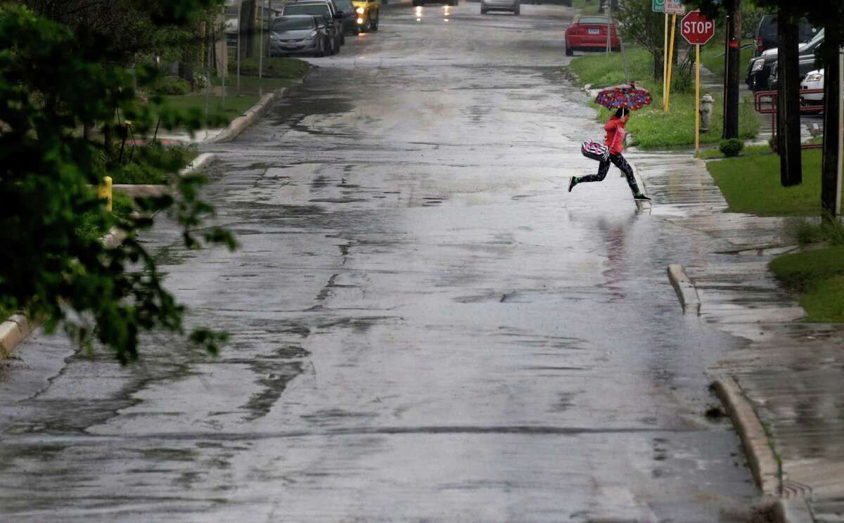 An umbrella-clad individual makes a leap over a puddle of water on Howard Street as thunder storms loomed over the city on Friday, Apr. 17, 2015. (Kin Man Hui/San Antonio Express-News)