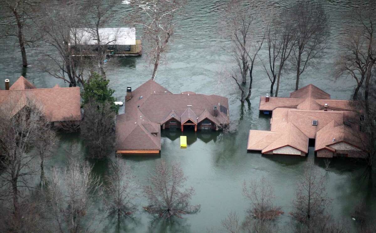 In this Tuesday, Dec. 29, 2015 photo, floodwaters from Lake Taneycomo surrounded several homes in a Branson, Mo., neighborhood after a record amount of water was released from the Table Rock Lake Dam. (Nathan Papes/The Springfield News-Leader via AP) MANDATORY CREDIT ORG XMIT: MOSPL104