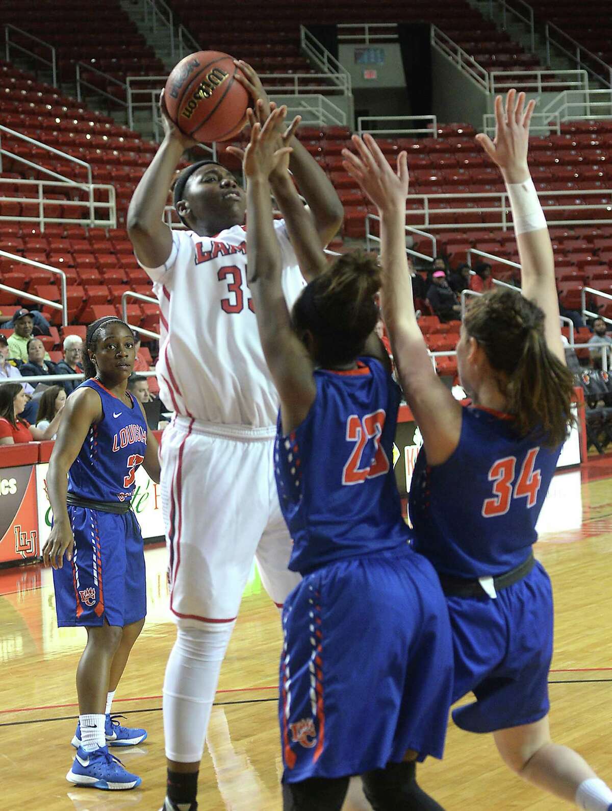 Lamar University's Laka Blache puts up her shot over the blocking efforts of Louisiana College's Shalondria Polly and Josey Broussard during the Lady Cardinals' home opener Thursday night at the Montagne Center. Photo taken Thursday, November 19, 2015 Kim Brent/The Enterprise