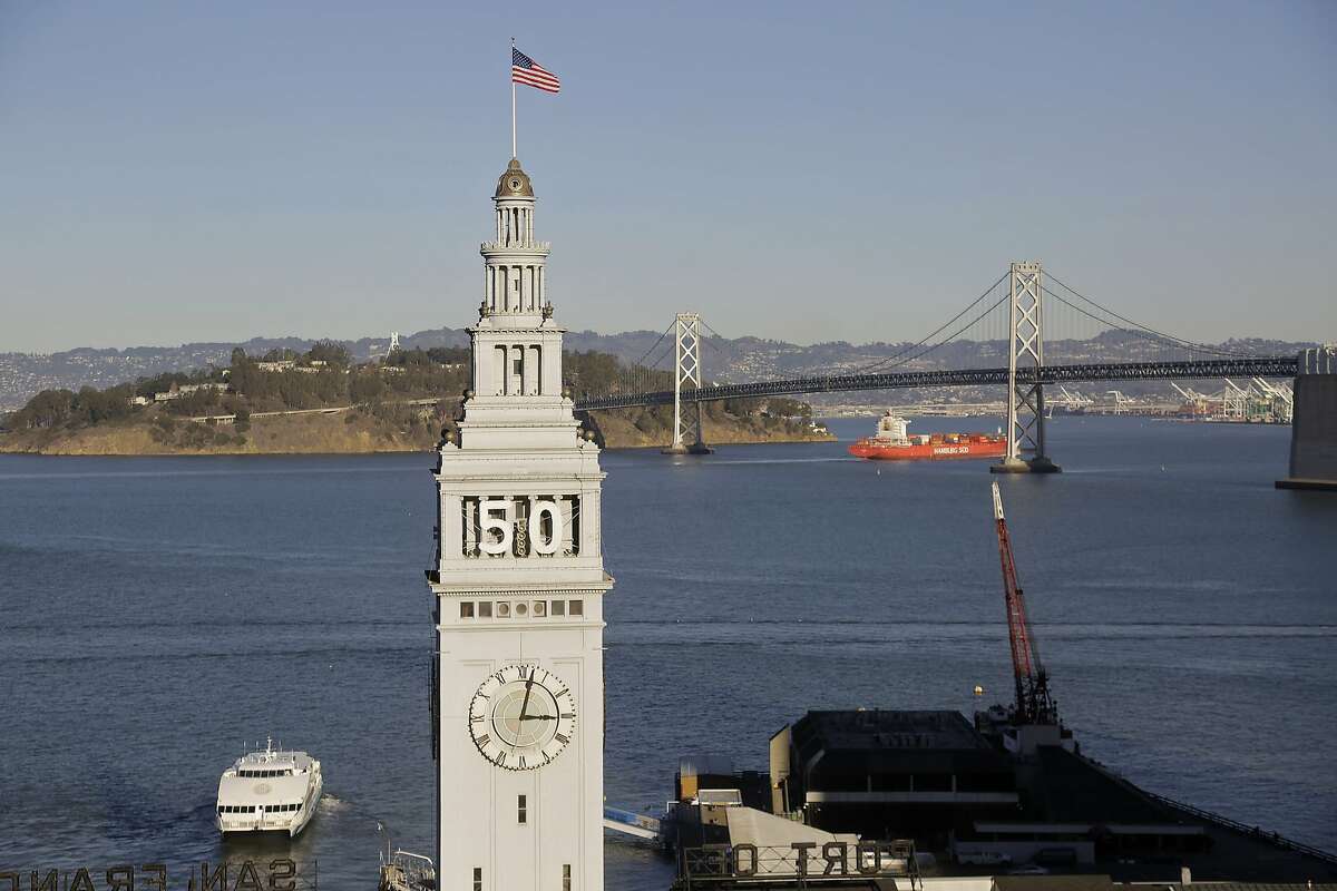 In this photo taken Wednesday, Dec. 16, 2015, is the Ferry Building in San Francisco. In the background is the San Francisco-Oakland Bay Bridge. Atop the waterfront tower is the number 50 for the upcoming Super Bowl in February 2016. (AP Photo/Eric Risberg)