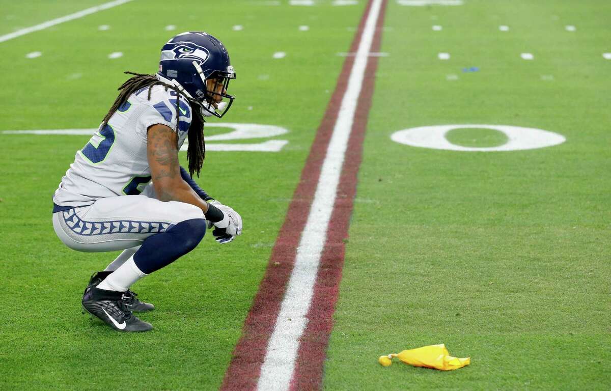 Seattle Seahawks cornerback Richard Sherman kneels after a flag was thrown on him during the first half of an NFL football game against the Arizona Cardinals, Sunday, Jan. 3, 2016, in Glendale, Ariz.