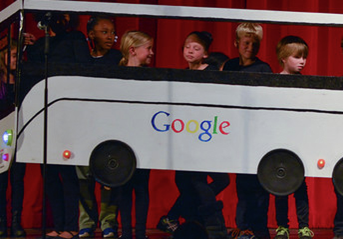 Third graders perform a scene featuring a Google bus and a city Muni bus.