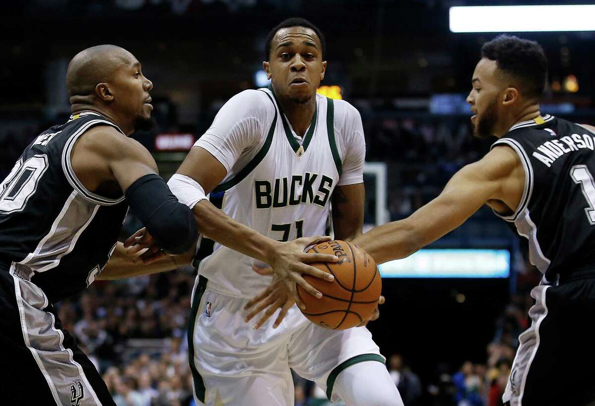Milwaukee Bucks’ John Henson is fouled as he drives between San Antonio Spurs’ David West (30) and Kyle Anderson during the first half of an NBA basketball game Monday, Jan. 4, 2016, in Milwaukee.