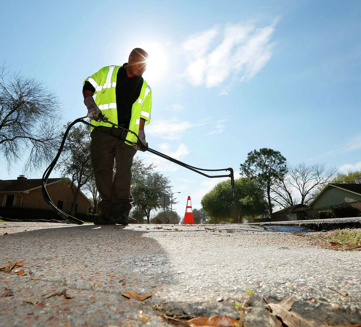 Timothy Drones sprays SS-1, an emulsion which helps asphalt adhere to the road, over an area his City of Houston road crew is about to patch at the corner of Belle Park Drive and Bandlon Drive, Tuesday, Jan. 5, 2016, in Houston.
