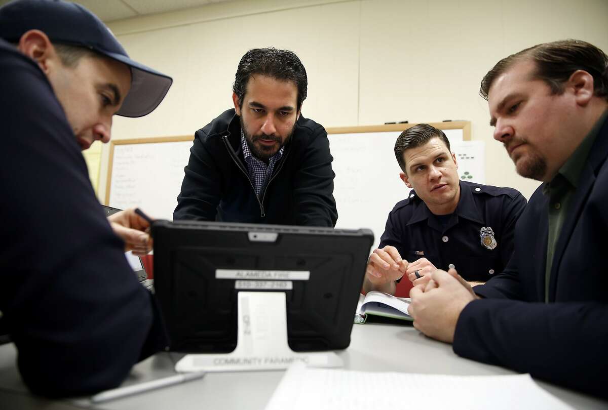 Jonathon Feit (center) works on a tablet as Patrick Corder (left) points out aspects of the program they're working on while Christian Witt (right) listens to Dave Wills during a community paramedicine meeting at City Hall West in Alameda, California, on Wednesday, Jan. 6, 2016.