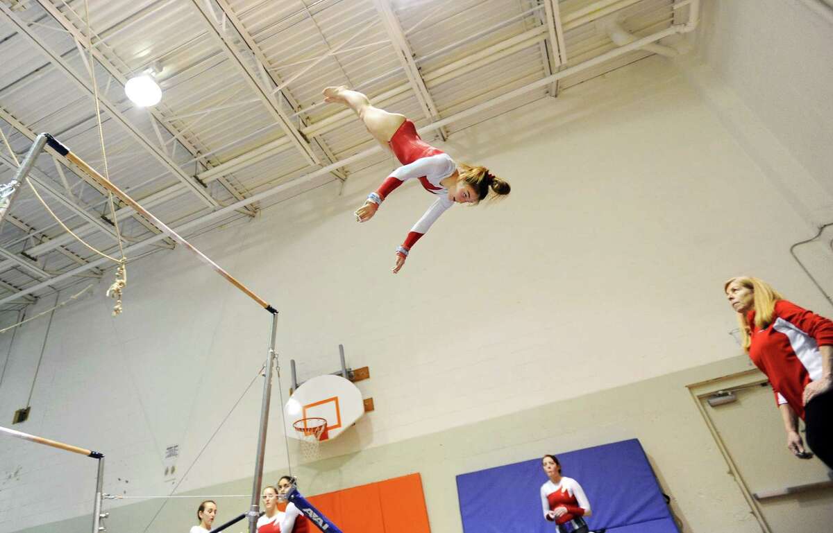 Greenwich junior Jessica Freiheit flies through the air at the end of her high-beam routine during a gymnastics meet against Fairfield Warde on Thursday at the Greenwich YWCA.