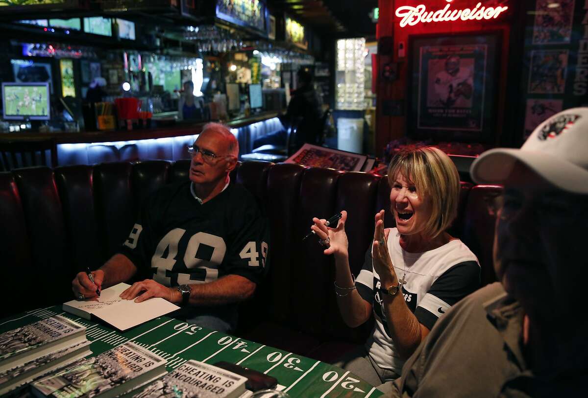 Former Raiders player Mike Siani, left, Kristine Setting Clark and Mark Pinheiro watch the Kansas City vs. Houston Wild Card game as they also promote Siani and Clark's recent book "Cheating is Encouraged" at Ricky's Sports Theatre & Grill Jan. 9, 2015 in San Leandro, Calif.