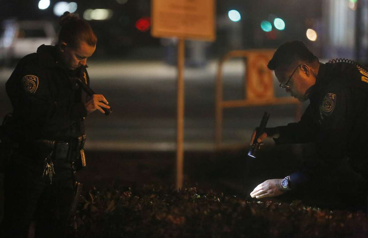 Police officers search the bushes near a bus stop on 7th Street outside of the West Oakland BART station, the closest stop where there was a fatal shooting on a BART train Jan. 9, 2015 in Oakland, Calif.