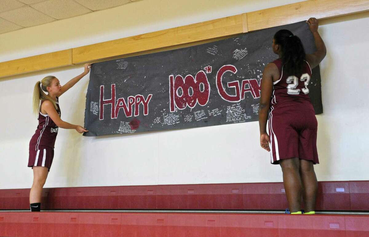 Morgan McCutheon, left, and Brittany Reid hang a banner celebrating Wooster School girls varsity basketball coach David McNutt's 1,000th career varsity basketball game on Wednesday afternoon, January 13, 2016, in Danbury, Conn.