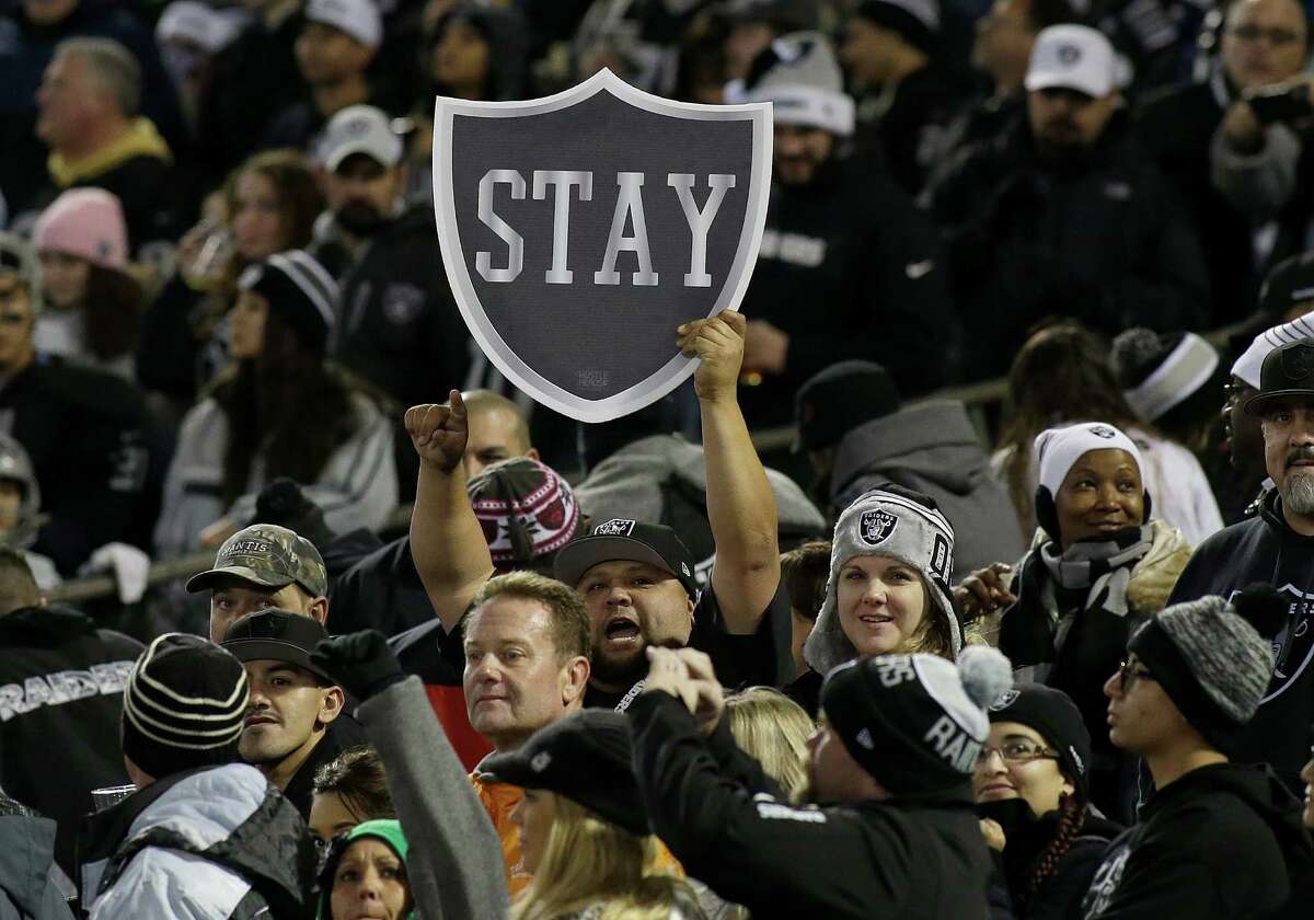 Fans hold up a sign for the Raiders to stay in Oakland before the home game against San Diego Chargers on Dec. 24, 2015.