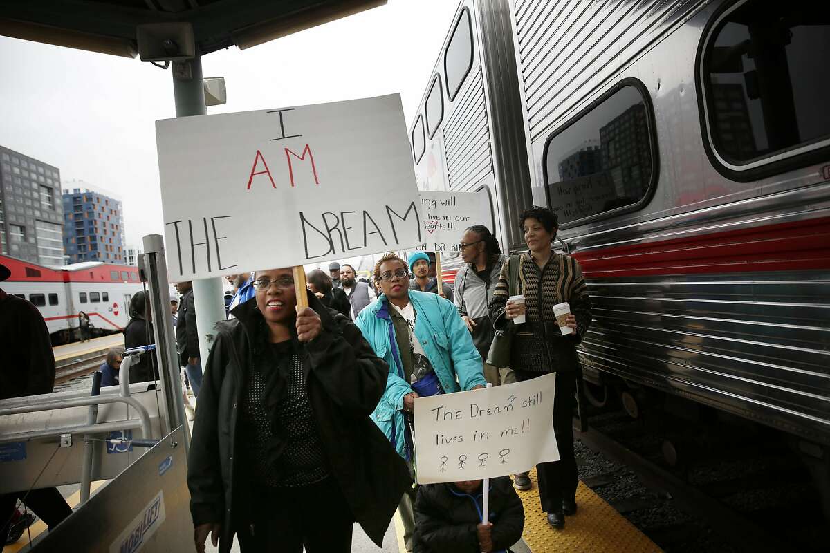 Binnie Flippin (left), Bonnie Flippin (second from left) and Dominic Hampton, 4, all of Oakland, carry signs as they disembark from the Freedom Train on Monday, January 19, 2014 in San Francisco, Calif.