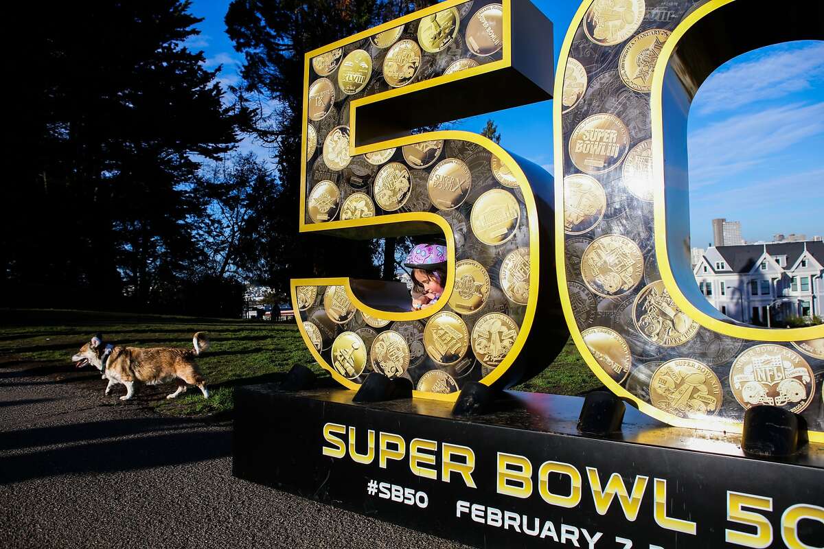 Olivia Cunningham, 4, and her dog Gaigho (left) spend time exploring a sculpture of the number "50" in Alamo Square Park, in San Francisco, California on Friday, January 15, 2016.