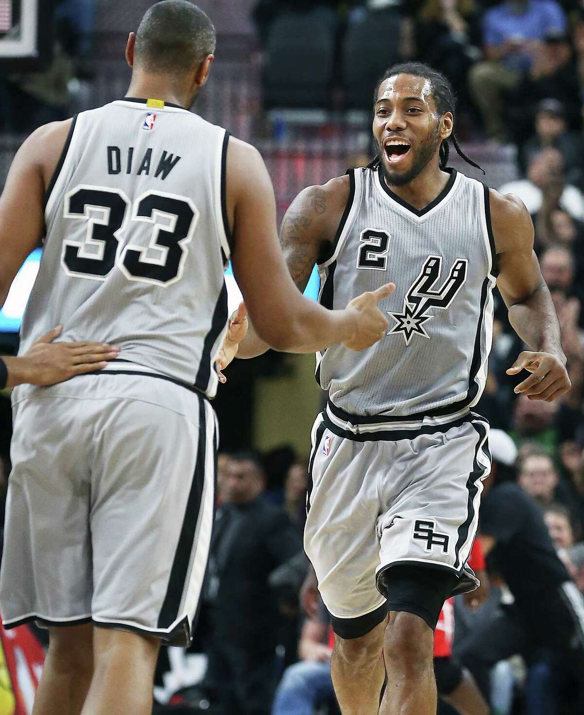 Kawhi Leonard laughs as he is congratulated by Boris Diaw on a three pointer in the second half as the Spurs host the Rockets at the AT&T Center on January 2, 2016.