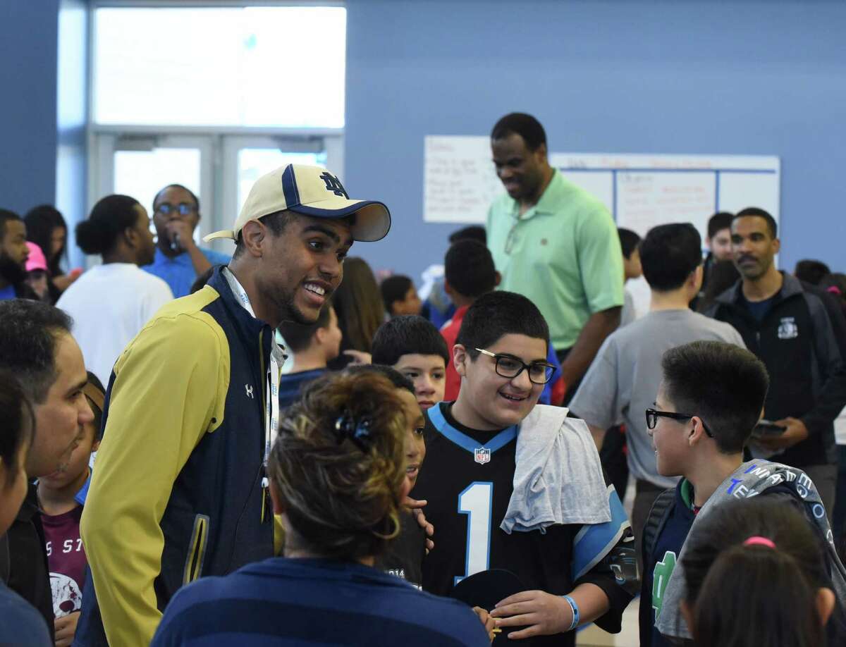 Notre Dame football wide receiver Corey Robinson and his father, former San Antonio Spurs player David Robinson, in background, converse with students at IDEA Carver on Saturday, Jan. 16, 2016, where they and college student athletes encouraged students and distributed T-shirts with logos of various universities through the One Shirt, One Body initiative. The One Shirt, One Body program was created by Corey Robinson and Andrew Helmin, a former Notre Dame track and field athlete, to unite student athletes and schools by donating excess college gear where there is a need. Over 1,000 university tees were given at four San Antonio area IDEA Public Schools.