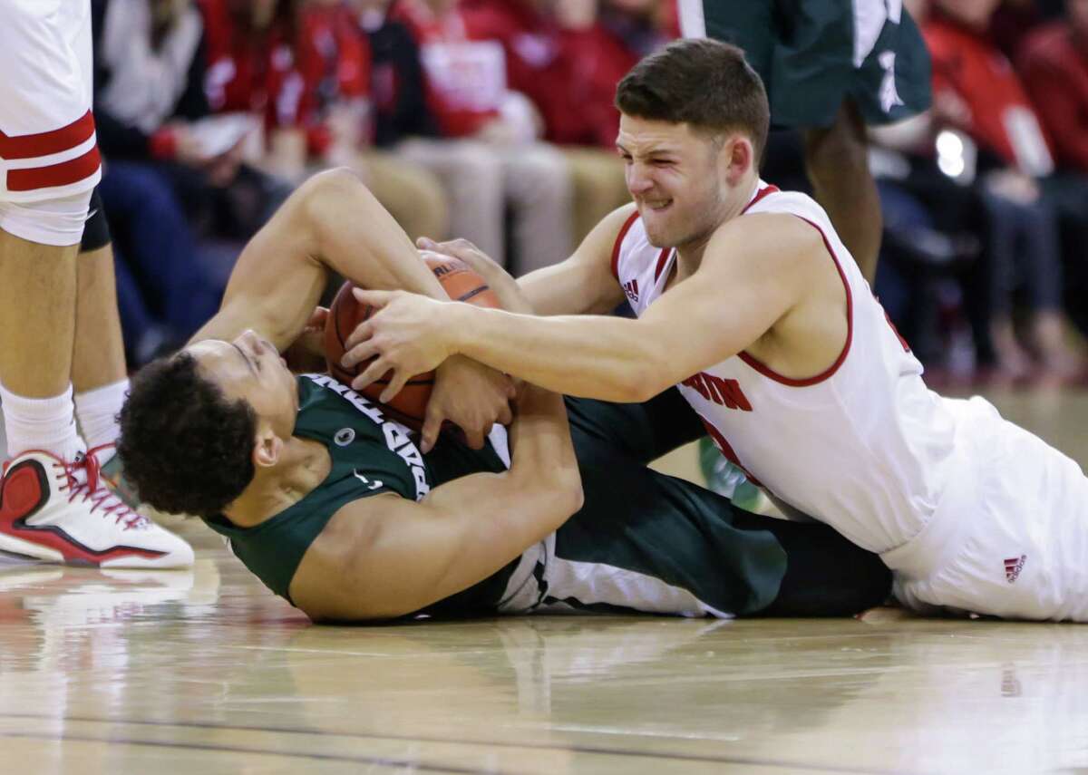 Michigan State's Bryn Forbes, left, and Wisconsin's Zak Showalter, right, battle for a loose ball during an NCAA college basketball game Sunday, Jan. 17, 2016, in Madison, Wis. Wisconsin upset Michigan State 77-76. (AP Photo/Andy Manis) ORG XMIT: WIAM118