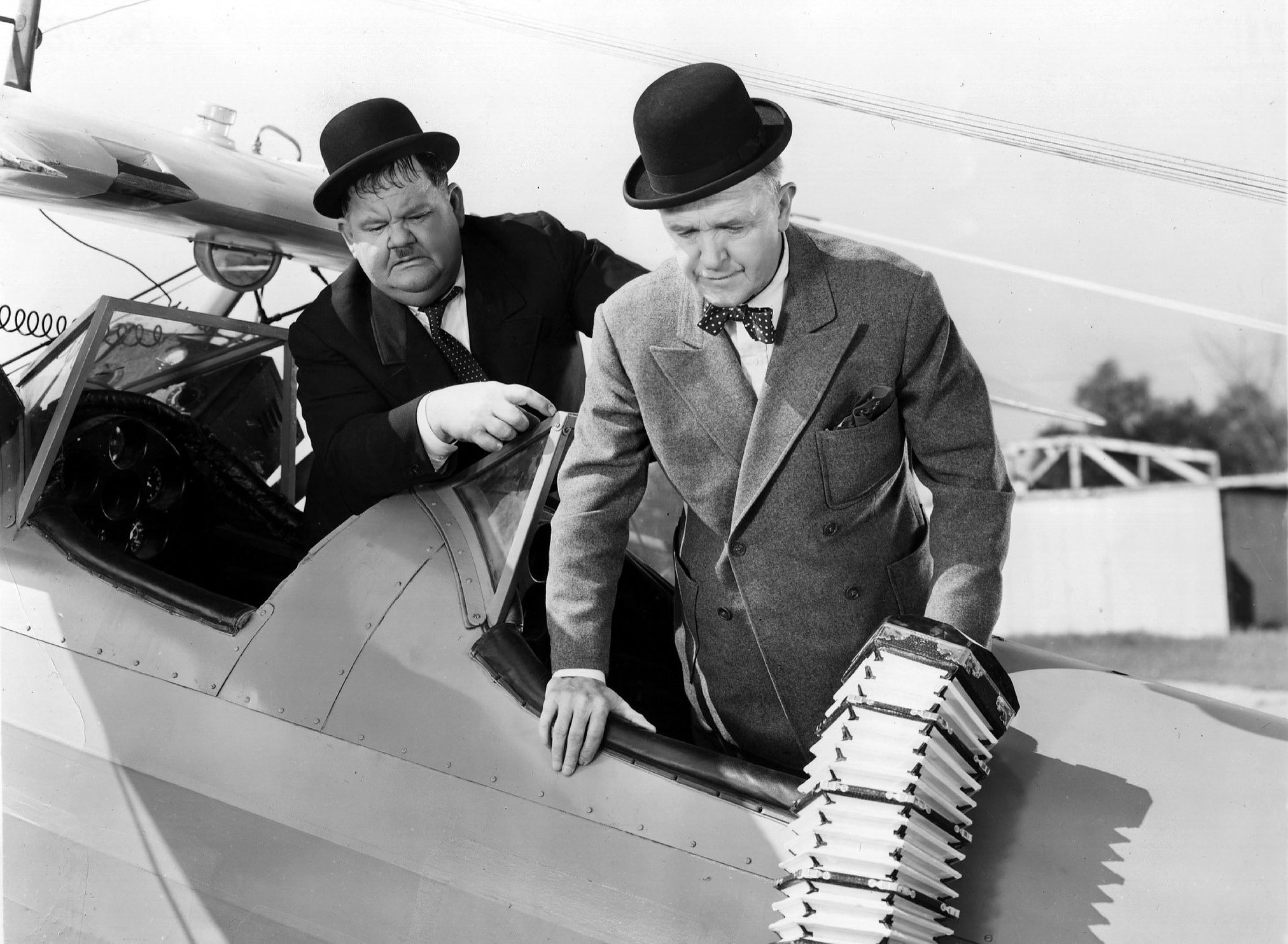 Stan Laurel and Oliver Hardy prepare to board a small aircraft holding an accordion in a scene from 'The Big Noise'. The film was directed by Mal St Clair for 20th Century Fox, 1944