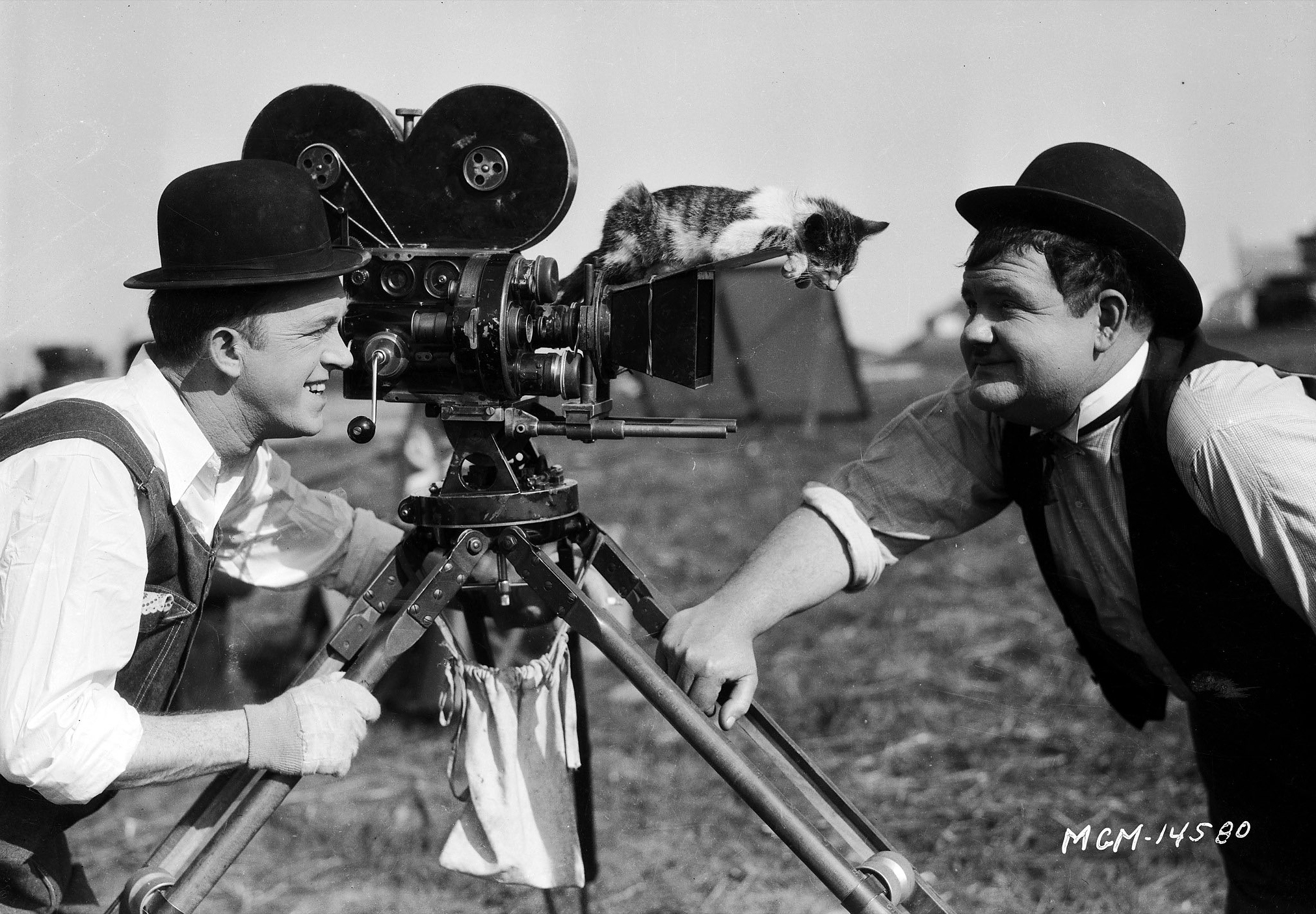 Stan Laurel and Oliver Hardy with a kitten during filming of the silent short 'The Finishing Touch', directed by Leo McCarey and Clyde Bruckman, 1928.