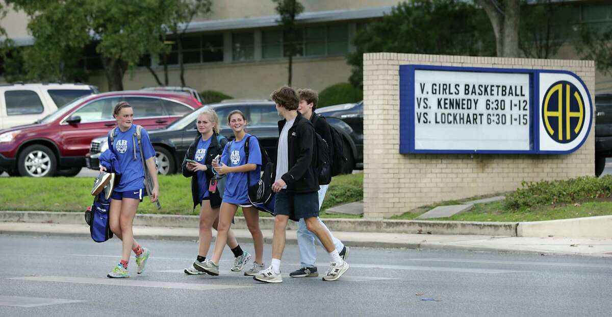 FILE - Students from Alamo Heights High School walk across Broadway after the final bell rang on Thursday, Jan. 14, 2015. The school is adding an armed police officer for the remainder of the school year following the massacre of 17 people, including students and teachers, at a Florida high school.