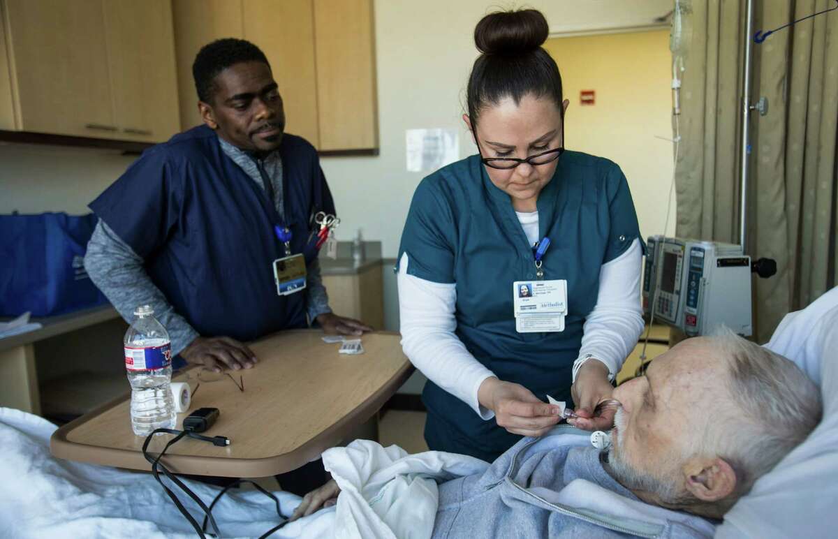 David Raven, ﻿left, and Anya Montoya ﻿work with patient Neil Harrison at Houston Methodist Cancer Center on Friday. As energy companies expect more layoffs, the health care sector continues to see robust hiring.
