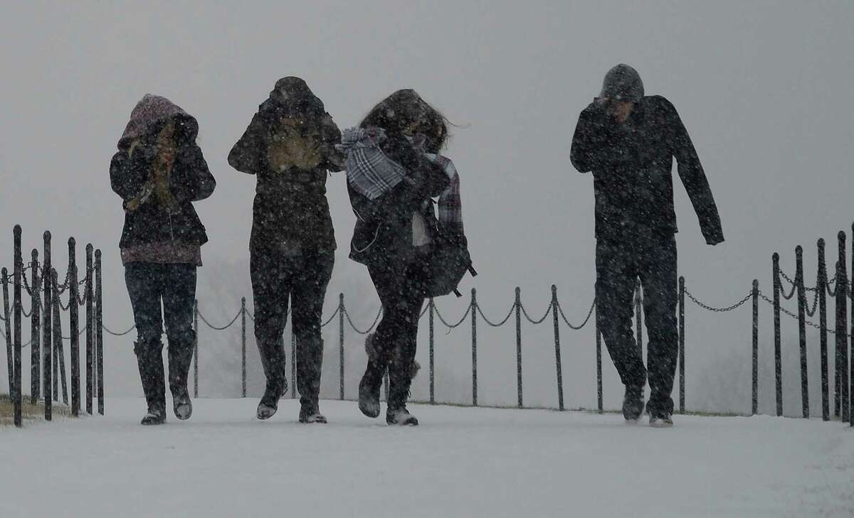 Visitors walk under snowfall in front of the Washington monument on Jan. 22, 2016 in Washington, D.C. Thousands of flights were cancelled as millions of Americans hunkered down for a winter storm expected to dump historic amounts of snow in the eastern United States. (Olivier Douliery/Abaca Press/TNS)