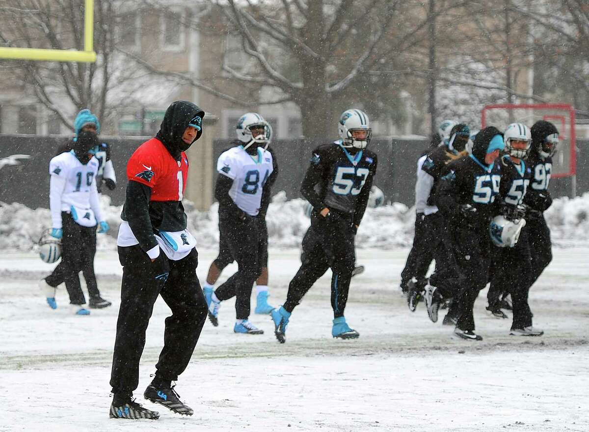 Carolina Panthers quarterback Cam Newton, left, walks across a practice field covered in snow and ice, Friday, Jan. 22, 2016, in Charlotte, N.C. The Panthers host the Arizona Cardinals in the NFC championship NFL football game on Sunday. (Jeff Siner/The Charlotte Observer via AP) MAGS OUT; TV OUT; MANDATORY CREDIT