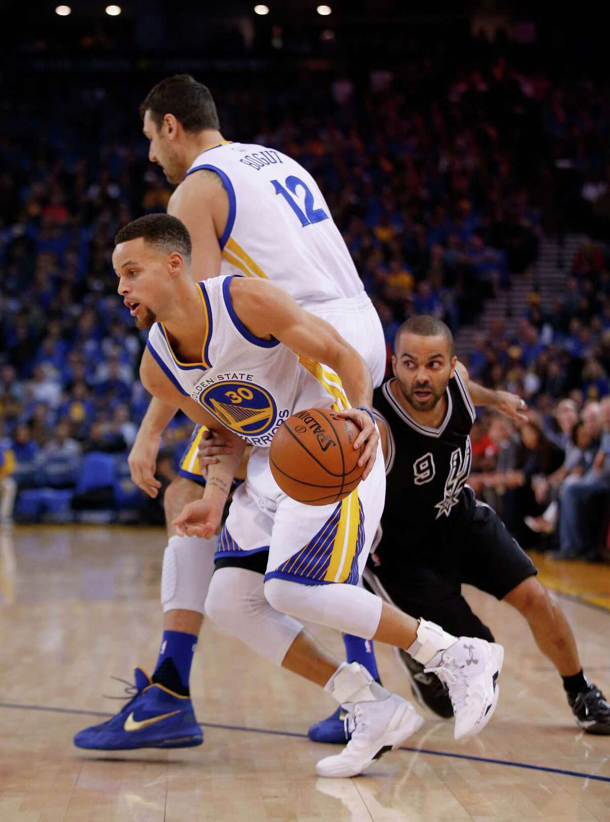 OAKLAND, CA - JANUARY 25: Stephen Curry #30 of the Golden State Warriors goes around a pick set by Andrew Bogut #12 while he is covered by Tony Parker #9 of the San Antonio Spurs at ORACLE Arena on January 25, 2016 in Oakland, California. NOTE TO USER: User expressly acknowledges and agrees that, by downloading and or using this photograph, User is consenting to the terms and conditions of the Getty Images License Agreement.