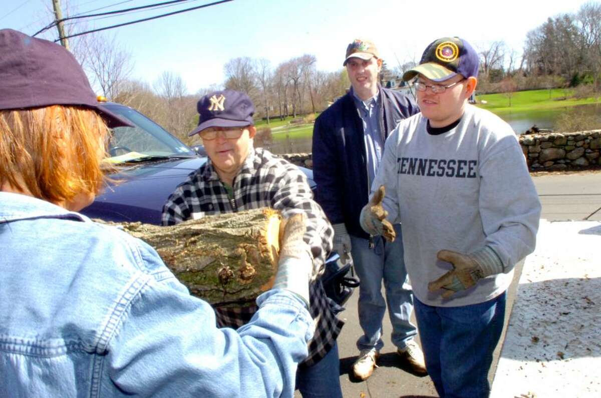 Abilis clients Margaret Makuck, left and Kevin Finn, carry a log to the truck, while Matt Hochman, slightly behind, and Chris Walker, right, assist, in Greenwich, at Thursday, April 1, 2010.